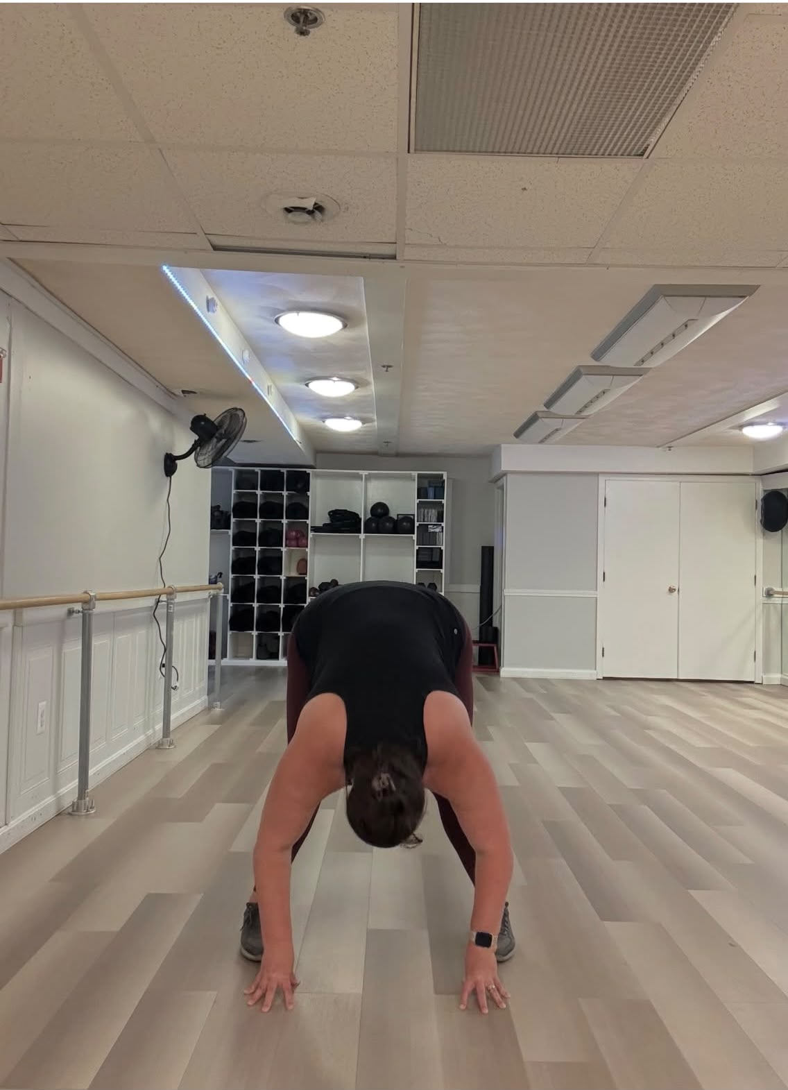 Diana folding forward in the barre and mirror studio at 33 Wellness