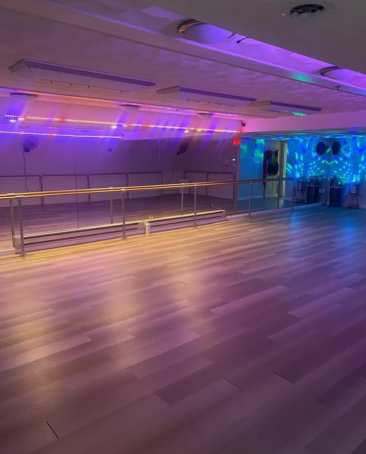 Studio at 33 Fitness + Wellness Center lit in pink and purple with barres and mirrors